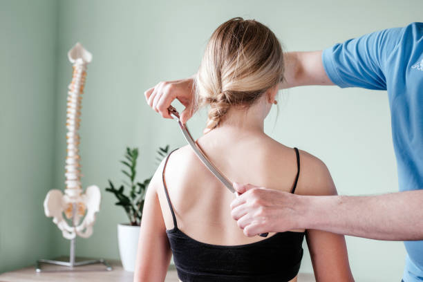 leczenie iastm, dziewczynka otrzymująca leczenie tkanek miękkich na szyi za pomocą narzędzia ze stali nierdzewnej - head massage headache massaging alternative therapy zdjęcia i obrazy z banku zdjęć