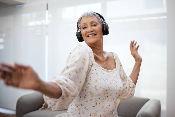 tiro de uma mulher idosa dançando enquanto usava fones de ouvido em casa - people moving audio - fotografias e filmes do acervo