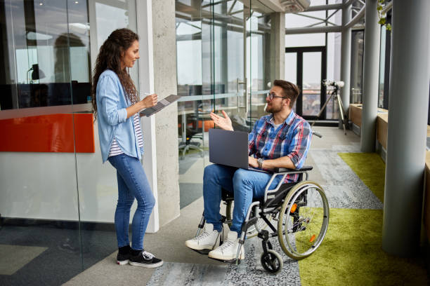 istock Disabled male computer programmer discussing with female coworker in office hallway 1329992034