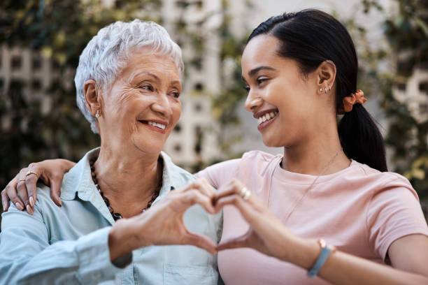 Shot of a senior woman and her daughter making a heart shape with their hands in the garden at home The love between mother and daughter lives forever heart hands multicultural women stock pictures, royalty-free photos & images