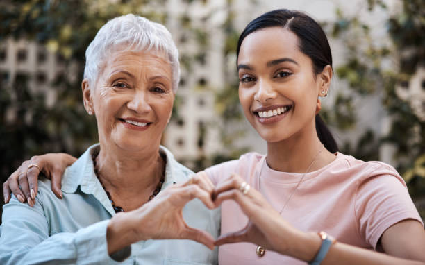 Shot of a senior woman and her daughter making a heart shape with their hands in the garden at home My mom's got all of my heart heart hands multicultural women stock pictures, royalty-free photos & images