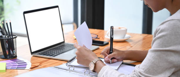 istock Cropped shot businesswoman writing information on document at het office desk. 1329993419