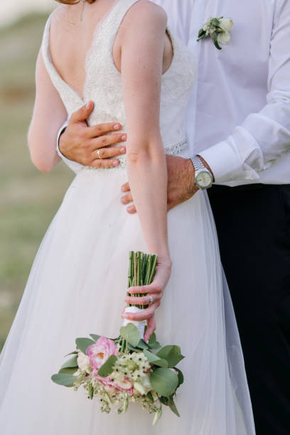 istock Groom hugging bride in white dress 1329995678
