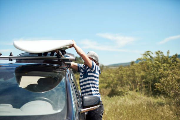 istock Windsurfer and camper packing and unpacking from a car in nature. 1329996469