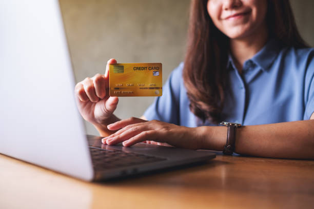 istock a business woman holding and showing a credit cards while using laptop computer for online payment 1329996848
