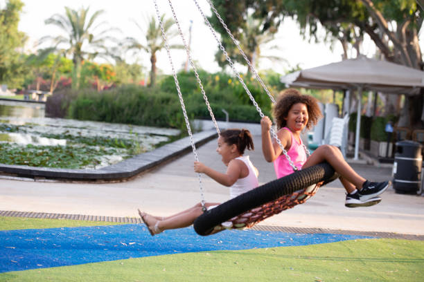 dzieci bawiące się na przejażdżkę huśtawką łańcuchową. - child swinging playground african descent zdjęcia i obrazy z banku zdjęć