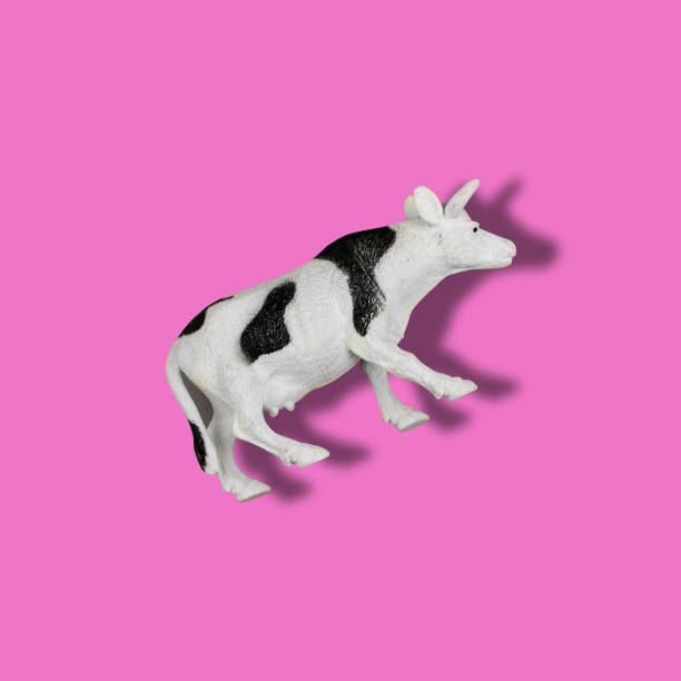 Toy cow on a colored background. Black and white spotted plastic