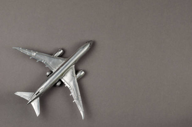 Minimalist composition with a silver children's toy airplane on a gray background. Top view, copy space