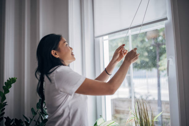 istock Woman lowering blinds on window 1330000908