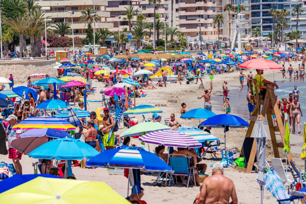 Calp, Spain. July 16, 2021. Multitude of people enjoying sun and beach. Calp is a popular summer time vacation destination for tourist coming mainly from Germany and England and local retreat for Spanish.