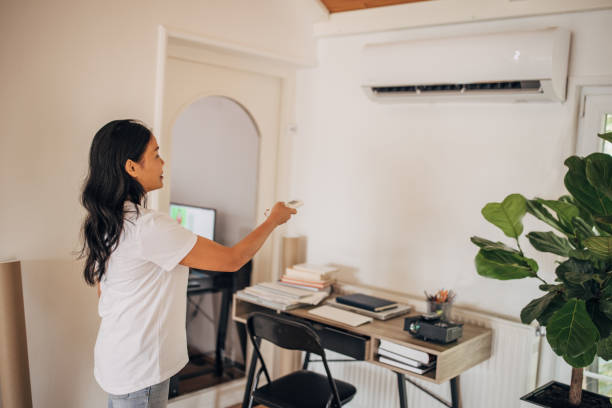 istock Woman turning on air conditioner 1330001023