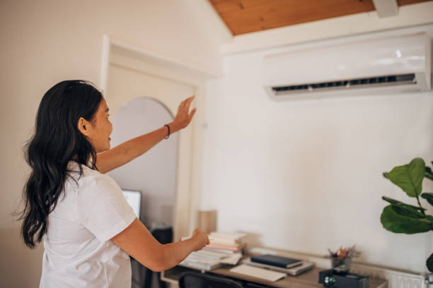 istock Woman turning on air conditioner 1330001038