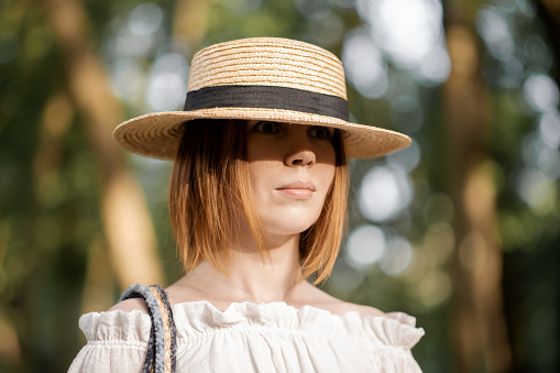 Middle-aged woman in a straw hat in the woods.