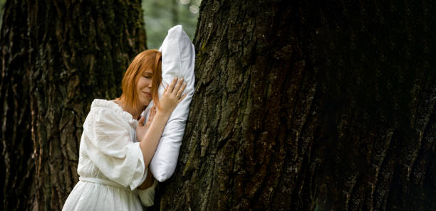 istock Woman sleeps soundly outdoors. She is lying on a pillow on a tree. Unity with nature, relaxation, recovery concept. 1330003681