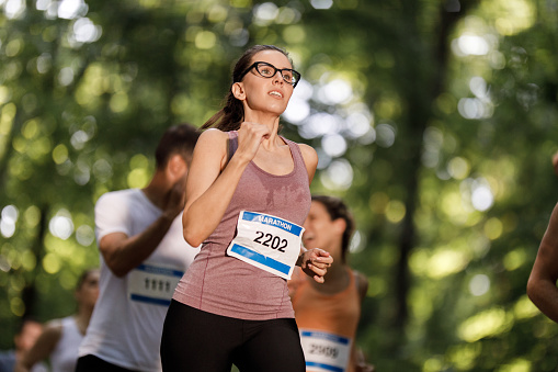 Determined sportswoman running a marathon in nature.