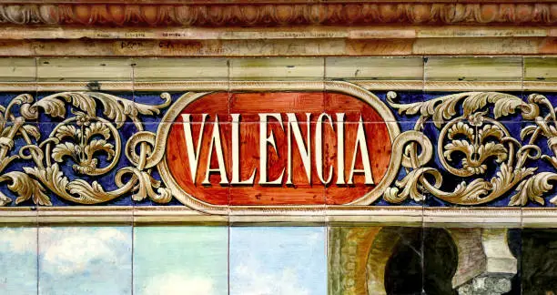 Photo of Tile with the name of the spanish city of Valencia on ceramic with a colorful decoration located in Spain Square in Seville