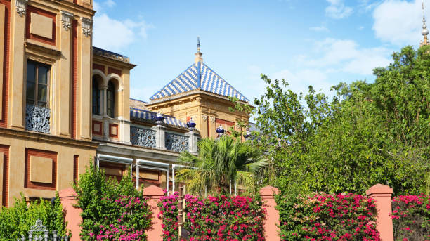 istock Bautiful architecture with a building surrounded by trees, pink flowers in a wall and a blue sky with clouds with a nice home feeling 1330005421