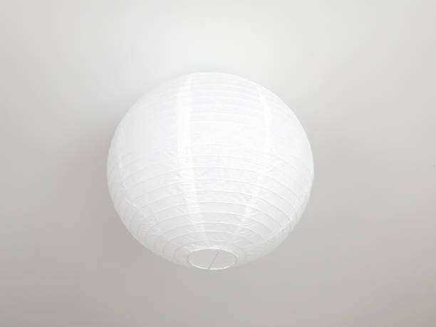 White round ceiling lamp on a white ceiling. Paper round lampshade. White round ceiling lamp on a white ceiling. Paper round lampshade. lamp shade stock pictures, royalty-free photos & images