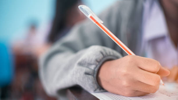 istock Students writing and reading exam answer sheets exercises in classroom of school with stress 1330010778