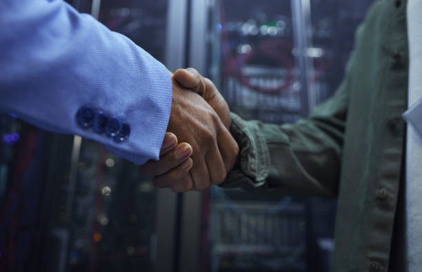 istock Cropped shot of two unrecognizable male IT support agents shaking hands in a dark network server room 1330012040