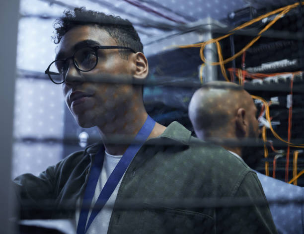 istock Cropped shot of two male IT support agents working together in a dark network server room 1330012042