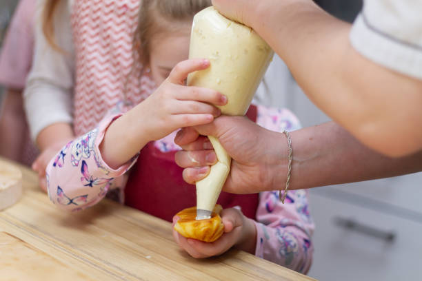 istock Filling cream eclairs from a pastry bag. Making eclair cakes yourself at home 1330014486