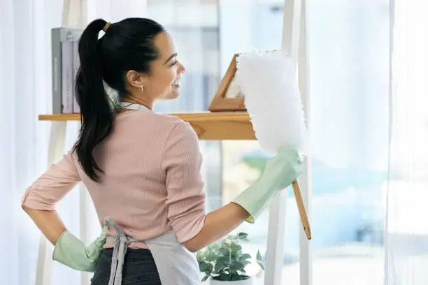 Photo of Shot of a woman holding a duster while doing chores at home