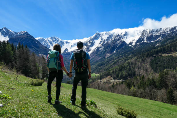 matschacher gupf - a couple with big hiking backpacks holding hands and enjoying the panoramic view on baeren valley - mountain mountain peak snow spring imagens e fotografias de stock