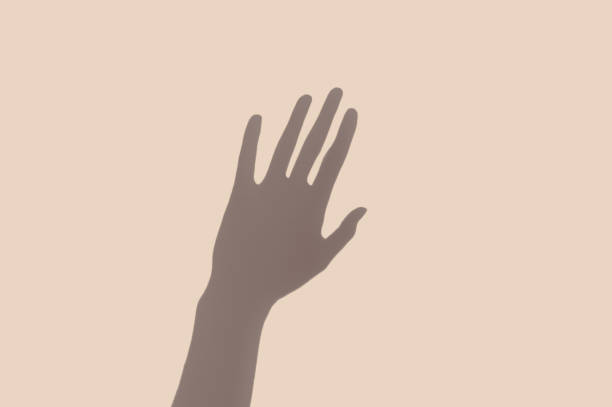 Creative minimal profile of a gray hand shadow on the pastel wall background. Abstract surreal style concept.