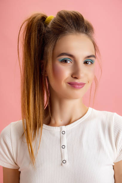 Portrait of adorable pretty young girl in retro 90s fashion style, outfits posing isolated over pink studio background. Concept of eras comparison, beauty, fashion and youth. Playful mood, flirt. Portrait of adorable pretty young girl in retro 90s fashion style, outfits posing isolated over pink studio background. Concept of eras comparison, beauty, fashion and youth. Looks excited, delighted vintage hairstyle stock pictures, royalty-free photos & images