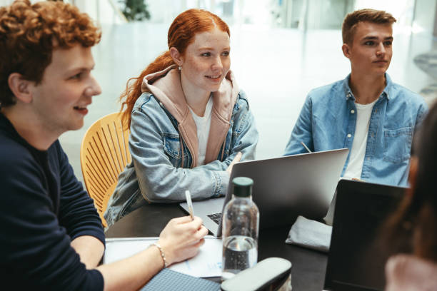 Group of friends working on a college assignment Students at group study in university campus. Group of friends working on a college project. teenager adolescence campus group of people stock pictures, royalty-free photos & images