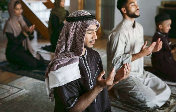 shot of a group of muslim family members praying together - islam praying mosque ramadan imagens e fotografias de stock