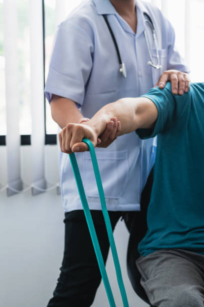istock A physiotherapist is helping a patient stretch his arm using cloth at the clinic. 1330020505