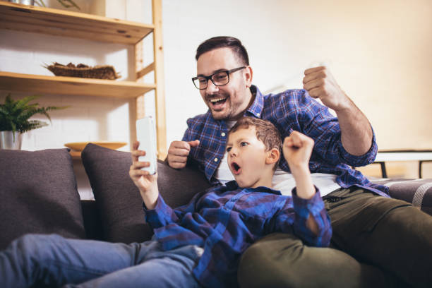 istock Father and son are using smartphones play video game and smiling while spending time together at home 1330021125