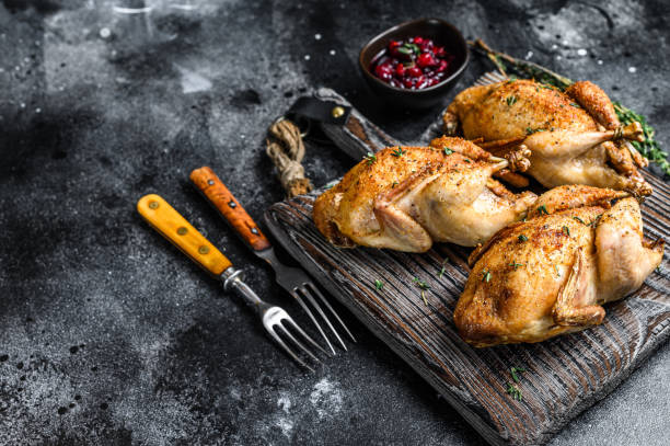 istock Whole Grilled quails on a wooden cutting board.  Black background. Top view. Copy space 1330021836
