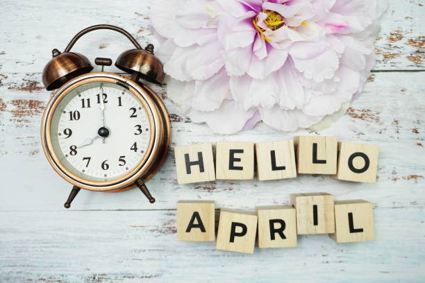 istock Hello April with alarm clock on wooden background 1330022021