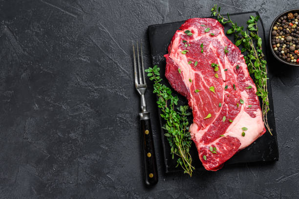 istock Raw Organic chuck eye roll meat steak cuts. Black background. Top view. Copy space 1330022706