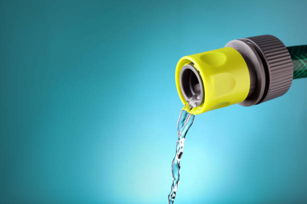 Water dripping from hose on light blue background, closeup. Space for text