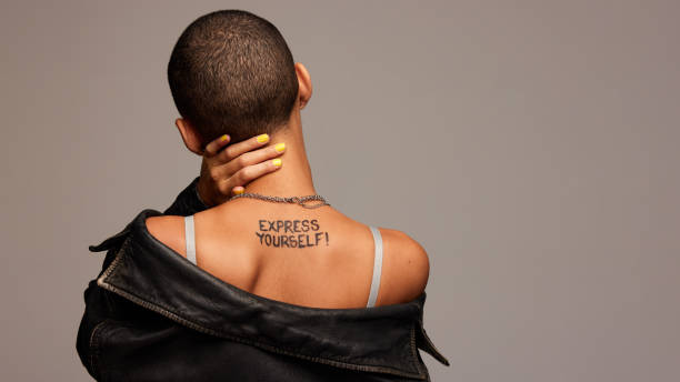 Androgynous woman with express yourself written on back Rear view of anonymous woman with express yourself written on back. Gender fluid person from behind on grey background. back of head photos stock pictures, royalty-free photos & images