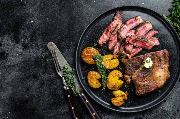 グリルリブアイビーフ肉ステーキをポテトと一緒にカットします。黒の背景。トップ ビュー。スペースをコピーする - rib eye steak steak beef prepared potato ストックフォトと画像