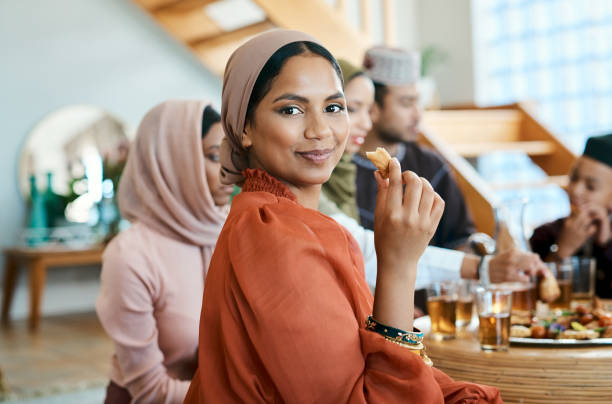 Shot of a young muslim woman enjoying lunch with her family Sharing a meal with others is special Eid Party stock pictures, royalty-free photos & images