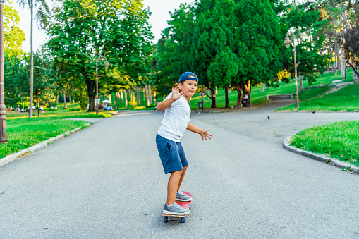 Kid skateboarder.Skater boy child with his skateboard. Outdoor activity. Little skater on skateboard have fun before children training class in skate park. Active family lifestyle, outdoor recreational activities on summer holidays in city. Kids sports and urban fashion.