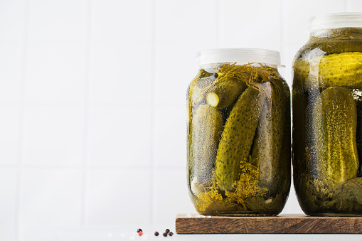 Pickled cucumbers in jars on a white background. Canning vegetables. Copy space. High quality photo