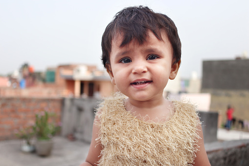 Portrait of cute innocent baby girl standing on rooftop at home.