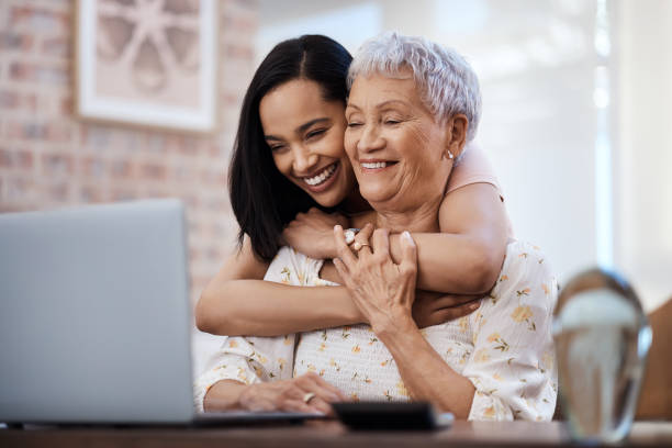 tiro de uma idosa usando um laptop com sua filha em casa - grandmother senior adult smiling women - fotografias e filmes do acervo