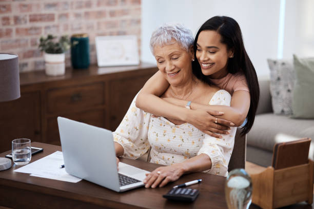 strzał młodej kobiety za pomocą laptopa ze starszą matką podczas przechodzenia przez finanse w domu - pension senior adult grandparent planning zdjęcia i obrazy z banku zdjęć