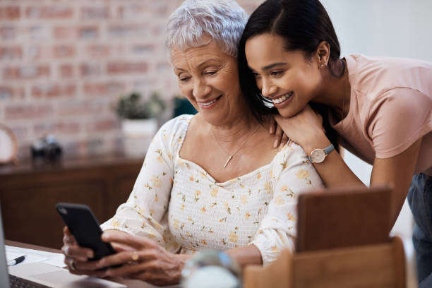 istock Shot of a young woman using a smartphone with her elderly mother while going through finances at home 1330030471
