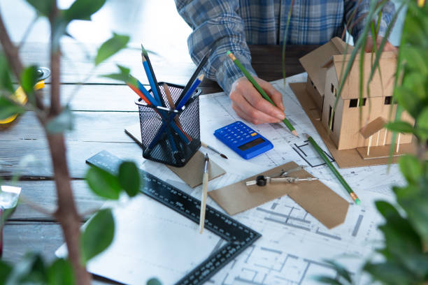 istock Workplace of architect - construction drawings, scale model and tools. Modern house design, real estate concept. 1330032159