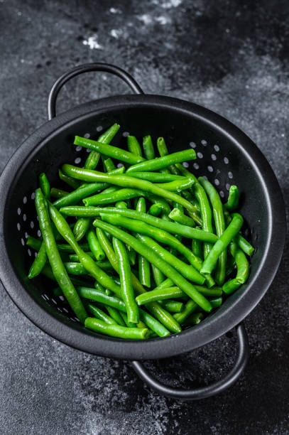 istock Raw green beans in a colander. Black background. top view 1330032341
