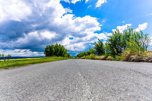 Empty road with a blue sky and clouds, low angle view, copy space. The photo is taken at agricultural field near Lovech, Bulgaria with Sony A7 SIII camera.